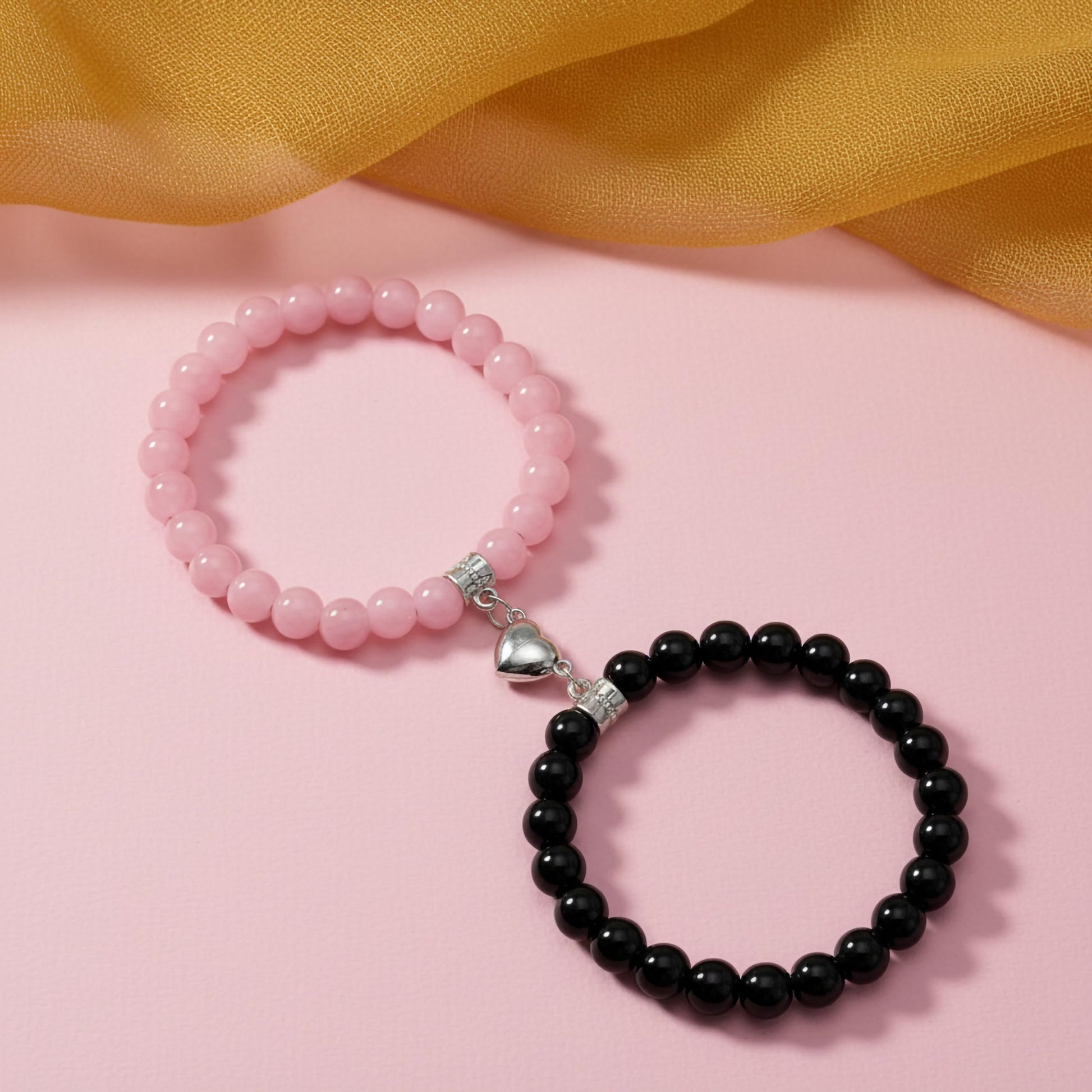 Create a sweet paired wrist look using black and pink 1-pair cord bracelets with connecting heart charms.