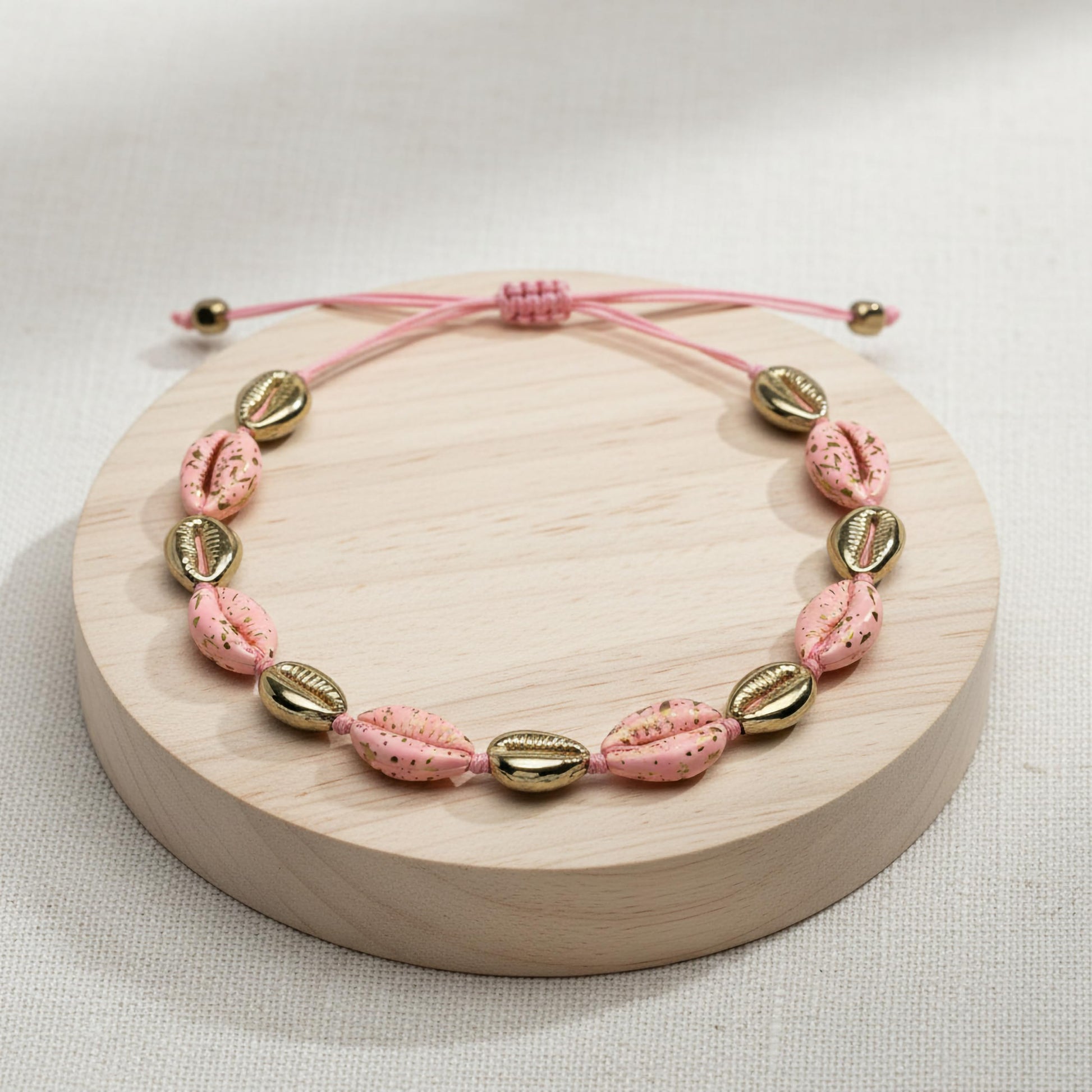 Decorative shell bracelet with pink tones and metallic finish