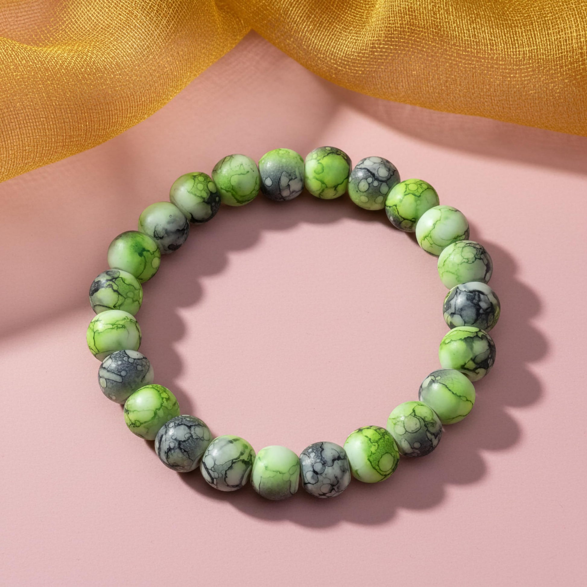 Bring playful color texture to stacked bracelets with green and black rounded marble-style beads.
