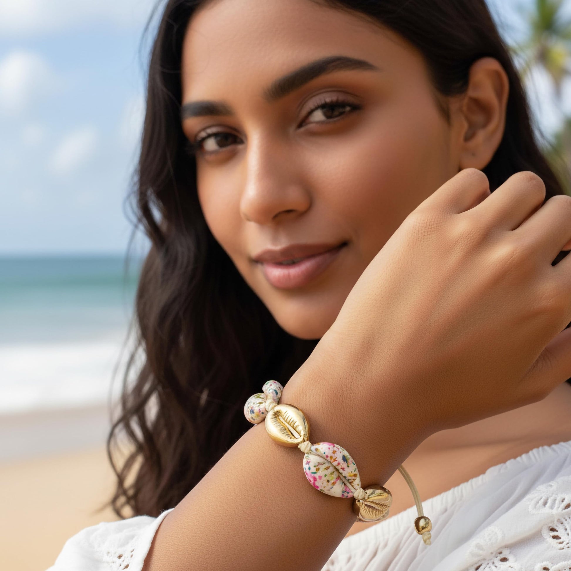 Handmade cowrie shell bracelet with gold accents and thread cord