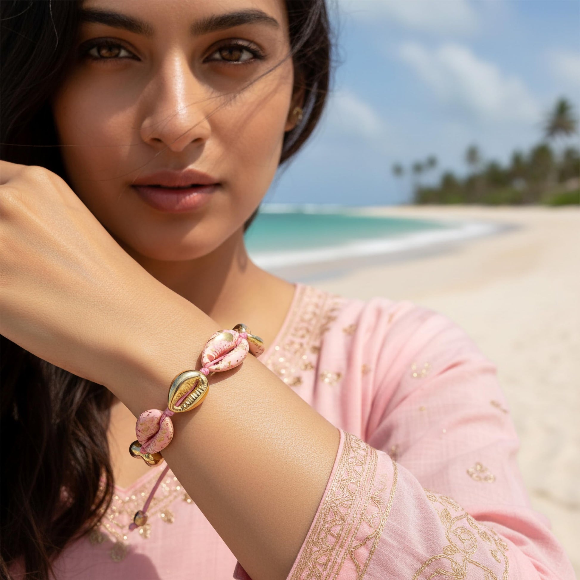 Adjustable pink cowrie shell bracelet with gold accents
