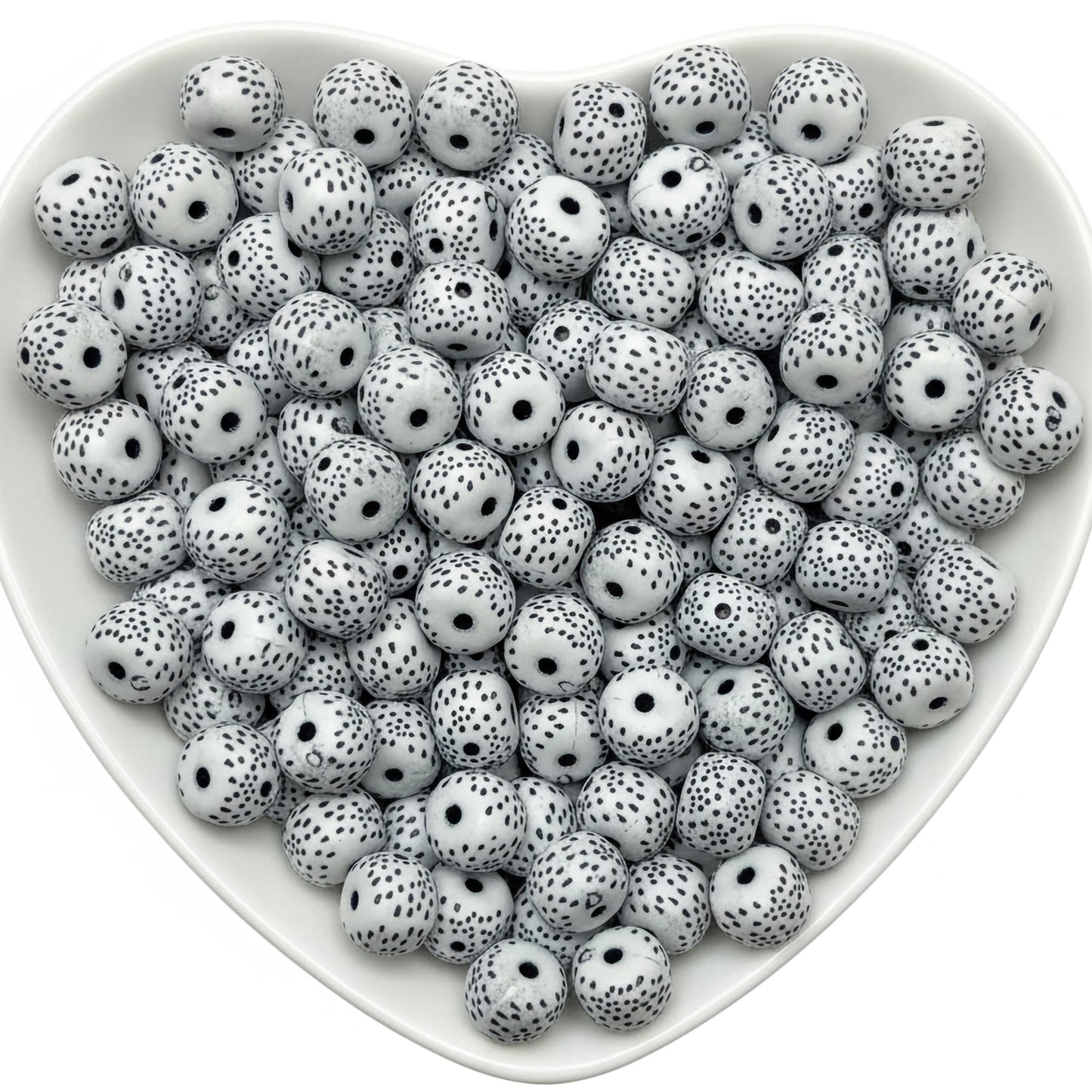 White round beads with black speckled pattern in heart tray